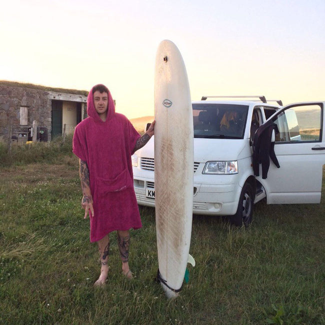 man holding a surboard wearing the booicore changing robe hot pink