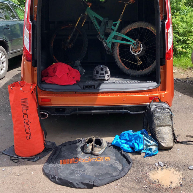 back of van open with mountain bike inside, booicore dirtbag orange and changing mat on floor outside van
