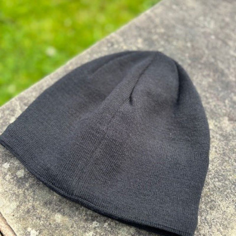the back of the knit black beanie from booicore on a garden wall