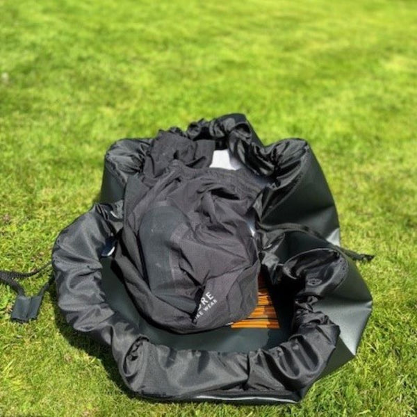 the booicore Changing Mat on grass after a swim holding wet swimwear before you pull the toggles together to make a bag to keep the wet items away from your dry items in the car on your way home