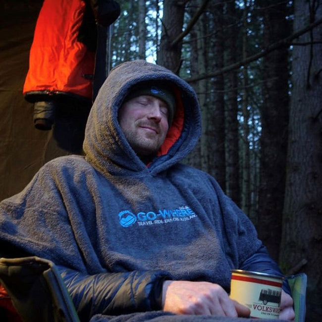 man sitting next to a campfire wearing booicore changing robe british grey